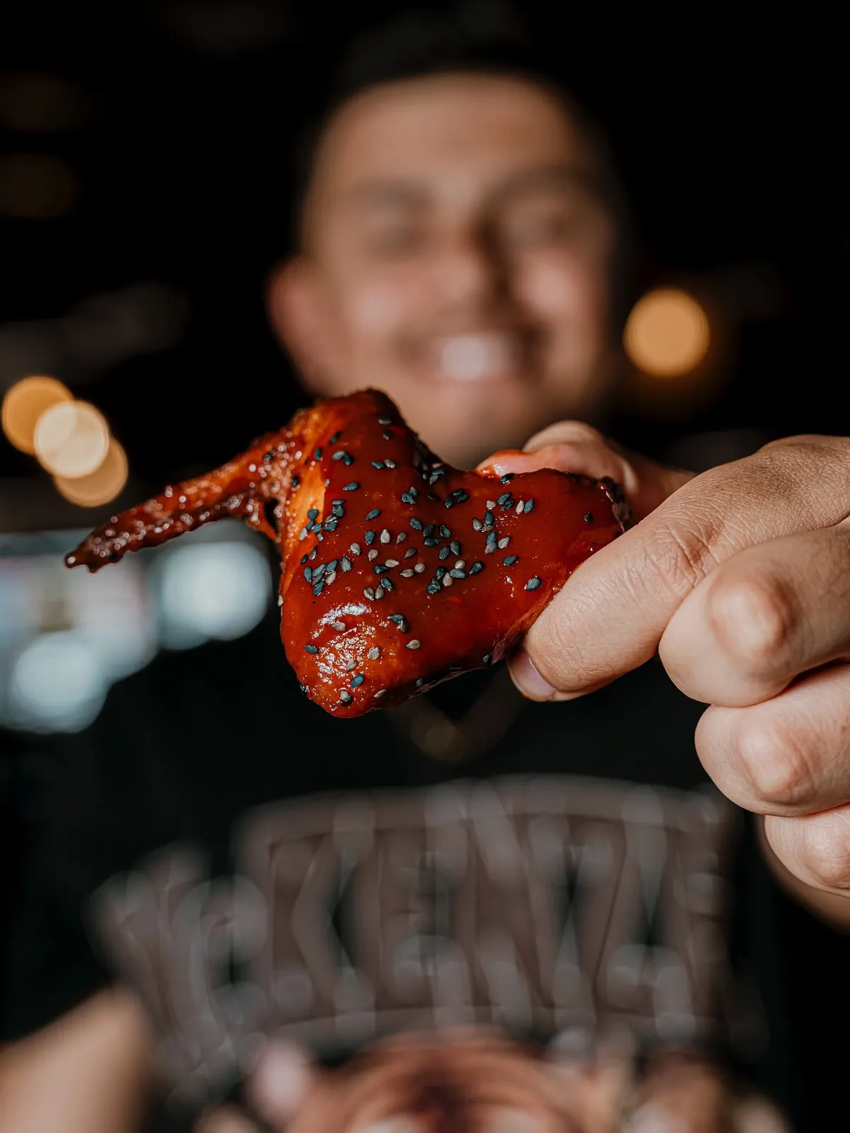 Cliente enseñando una alita de pollo glaseada