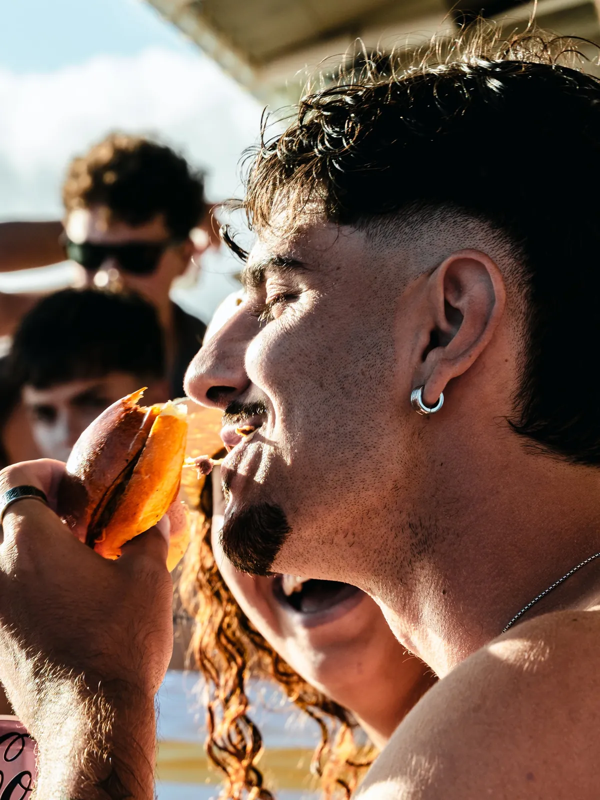 Cliente disfrutando de una burger al sol durante un evento