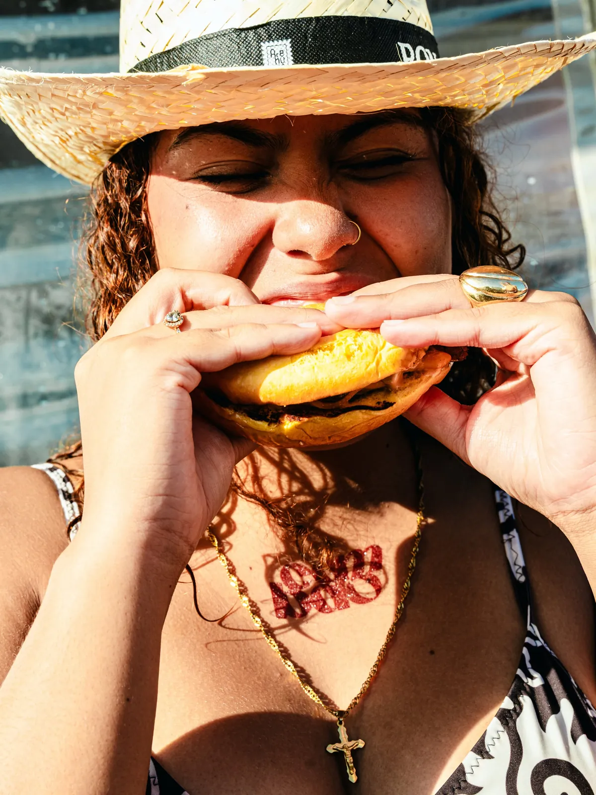 Clienta con sombrero de paja mordiendo una burger